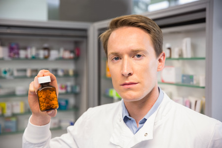 Handsome pharmacist holding medicine jar at the hospital pharmacyの写真素材
