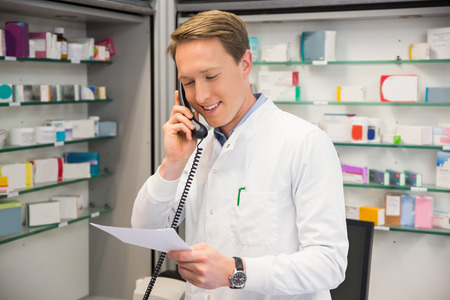 Happy pharmacist on the phone at the hospital pharmacyの写真素材
