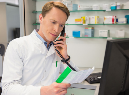 Serious pharmacist on the phone at the hospital pharmacyの写真素材