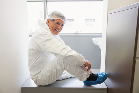 Pharmacist putting on his shoe covers at the laboratoryの写真素材