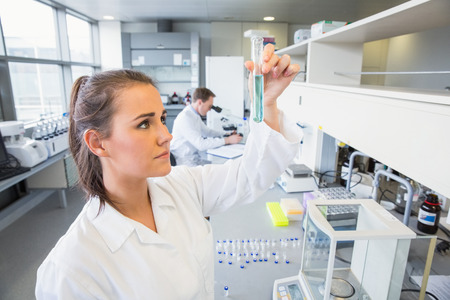 Young scientist holding up test tube at the laboratory