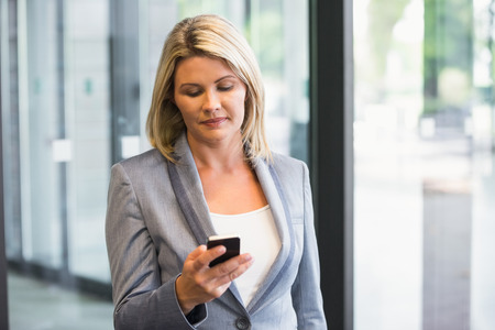 Blonde businesswoman on the phone in office buildingの写真素材