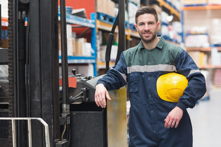 Manual worker leaning against the forklift in warehouseの写真素材