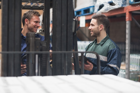 Smiling warehouse workers talking together in warehouseの写真素材