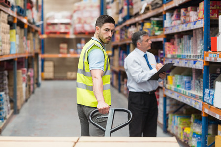 Warehouse worker talking with his manager in a large warehouseの写真素材
