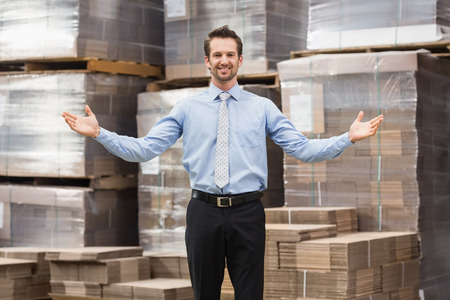 Smiling warehouse manager with hands out in a large warehouseの写真素材