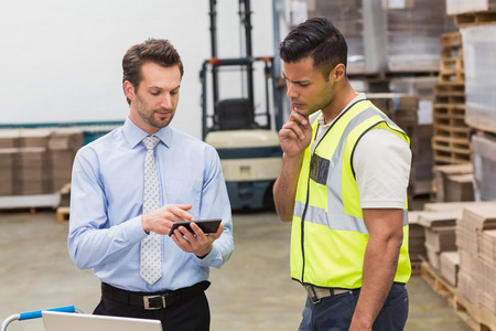 Warehouse worker talking with his manager in a large warehouseの写真素材