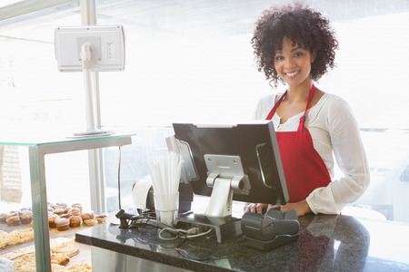Beautiful waitress posing behind the counter at the bakeryの写真素材