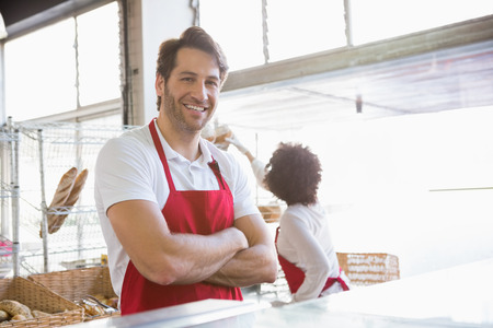 Portrait of a happy waiter with arms crossed at the bakeryの写真素材
