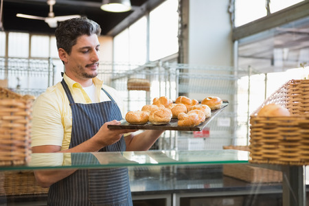 Cheerful waiter holding tray of breads at the bakeryの写真素材