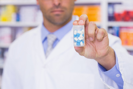 Handsome pharmacist holding medicine jar at the hospital pharmacyの写真素材