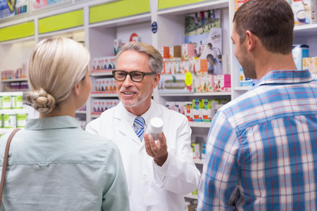 Senior pharmacist explaining the pills to patient at pharmacyの写真素材