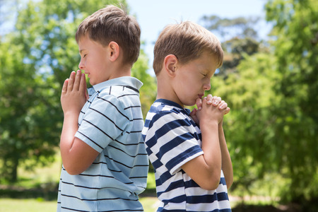Little boys praying in the park on a sunny dayの写真素材
