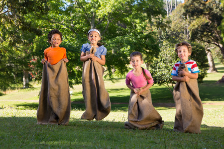 Children having a sack race in park on a sunny dayの写真素材