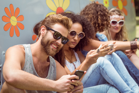 Hipster friends using their phones on a summers dayの写真素材