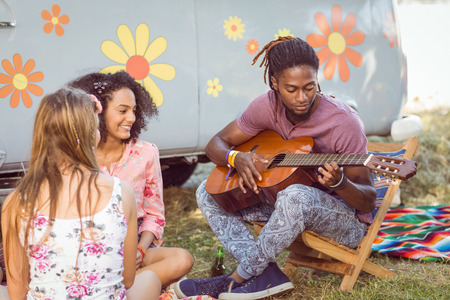 Hipster playing guitar for his friends at a music festivalの写真素材