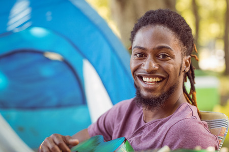 Happy hipster smiling at camera playing guitar at a music festivalの写真素材