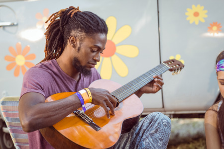 Hipster playing guitar for his friends at a music festivalの写真素材