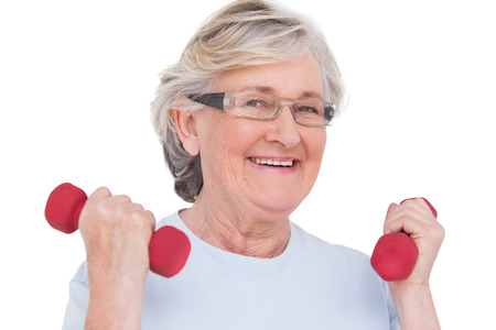 Senior woman lifting hand weights on white backgroundの写真素材