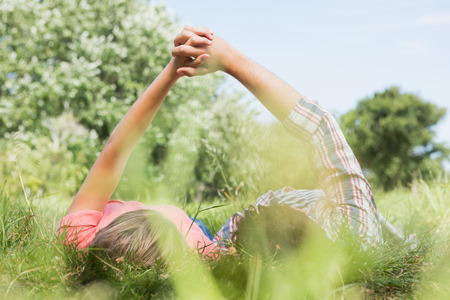 Cute couple holding hands in the park on a sunny dayの写真素材