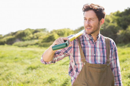 Happy farmer carrying his shovel on a sunny day
