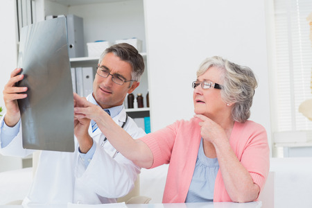 Male doctor explaining x-ray to senior patient in clinicの写真素材