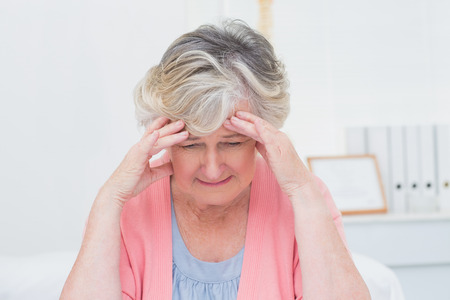 Tensed senior patient suffering from headache in clinicの写真素材