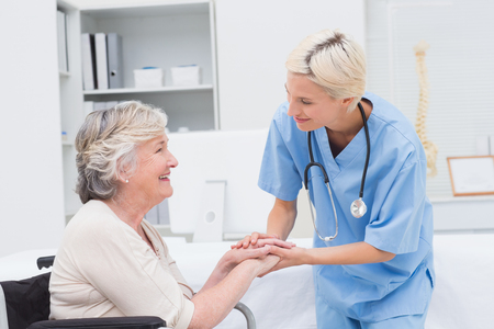 Friendly nurse holding senior patients hands in clinicの写真素材