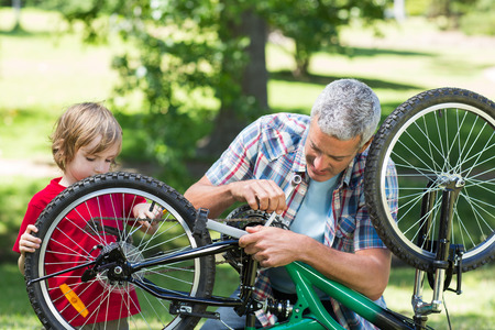 Father and his son fixing a bike on a sunny dayの写真素材