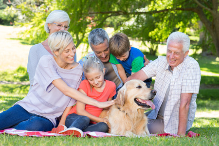 Happy family petting their dog in the park on a sunny day