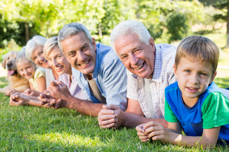 Smiling family looking at the camera with their dog on a sunny dayの写真素材