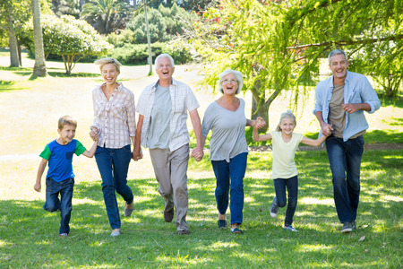 Happy family running in the park on a sunny dayの写真素材