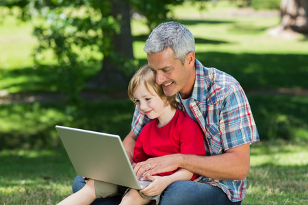 Happy father using laptop with his son on a sunny dayの写真素材