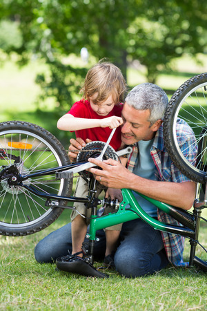 Happy father and his son fixing a bike on a sunny dayの写真素材