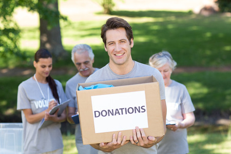 Happy volunteer man holding donation box on a sunny day