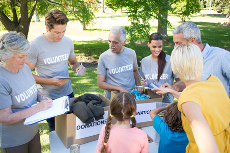 Happy volunteer family separating donations stuffs on a sunny dayの写真素材