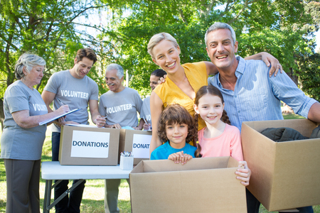 Happy family holding boxes and smiling at the camera on a sunny dayの写真素材
