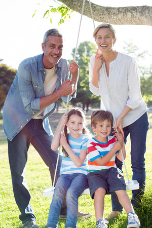 Happy family swing on a sunny dayの写真素材