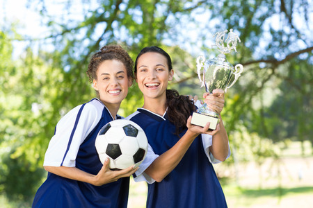 Pretty football players cheering at camera on a sunny dayの写真素材