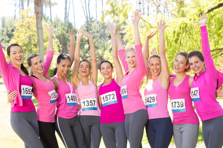 Smiling women running for breast cancer awareness on a sunny dayの写真素材