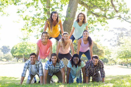 Happy friends in the park making human pyramid on a sunny dayの写真素材
