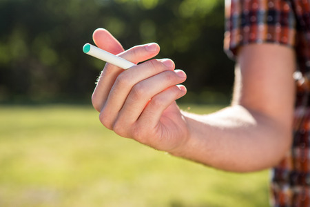 Hipster smoking an electronic cigarette on a summers day