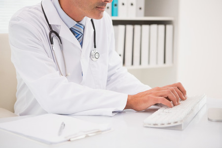 Doctor typing on keyboard in medical officeの写真素材