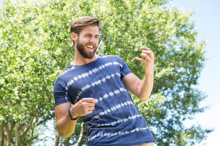 Handsome hipster playing air guitar on a summers day