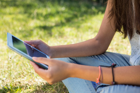Pretty brunette using tablet in park on a summers dayの写真素材