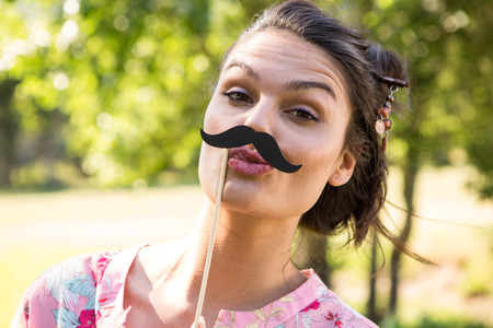 Pretty brunette with fake mustache on a summers dayの写真素材