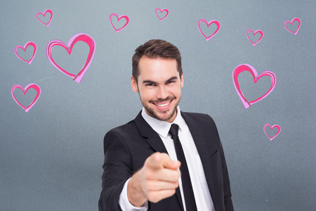 Happy businessman pointing at camera against greyの写真素材