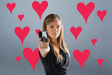 Femme fatale pointing gun at camera against greyの写真素材