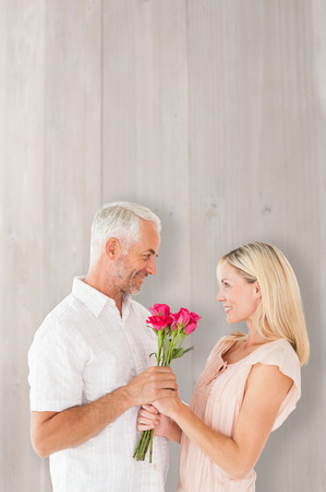 Affectionate man offering his partner roses against bleached wooden planks backgroundの写真素材