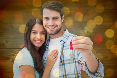 Happy young couple holding new house key against close up of christmas lightsの写真素材